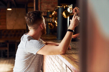 Man in casual clothes sitting in the pub at daytime