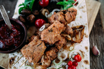 Pork shashlik on pita bread with vegetables close-up