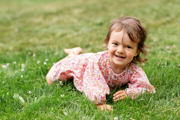 childhood, leisure and people concept - happy smiling little baby girl lying on grass in summer