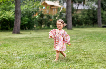 childhood, leisure and people concept - happy little baby girl running across summer field