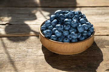 Blueberries in a round wooden plate close-up. Blueberries on a wooden background. Healthy food. Harvest on the table. Rustic kitchen table