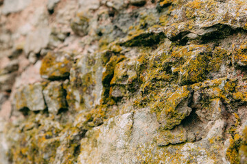 An old medieval stone wall, grass and moss on it. Wallpaper, natural background, copy space, soft focus.