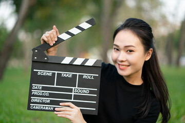 Asian woman holding movie clapper board in her hands, entertainment film concept