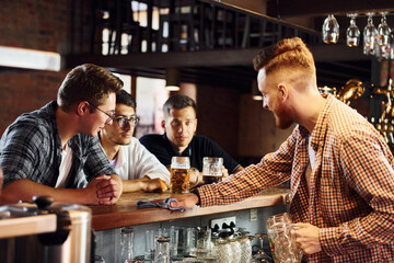 Cheerful young people in casual clothes sitting in the pub