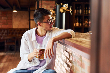 On the chair. Man in casual clothes sitting in the pub