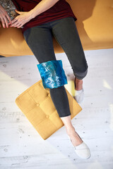 Woman with knee pain injury at home using ice gel pack.