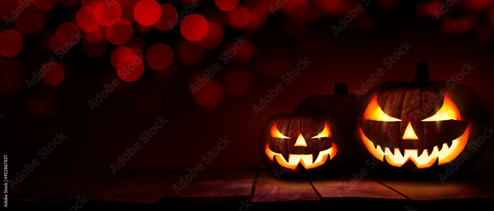 Wall mural three scary halloween lanterns with evil eyes and faces on a rustic wood table with a spooky dark re