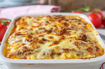 Lasagne with ragu alla bolognese, bechamel sauce and mozzarella cheese in a casserole dish. Closeup and front view
