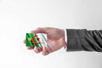 Man in elegant custom suit holding bank credit plastic card with flag of Algeria