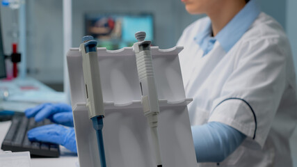 Close up of biochemist using micropipette in laboratory for scientific analysis in healthcare...