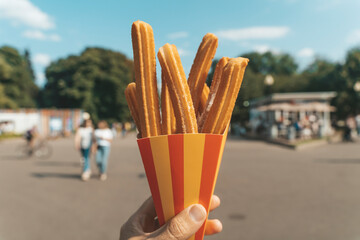 Churros waffles in hand on the street. Churros street food dessert made from dough and sugar. Fast food sweets