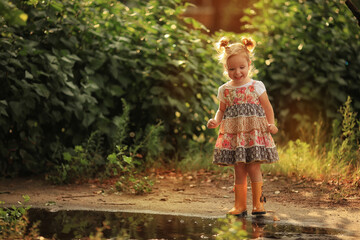 Obraz premium little girl near the puddle in yellow rubber boots