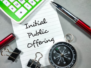 Business concept.Text Initial Public Offering writing on notepaper with paper clips,pen,compass and calculator on gray background.