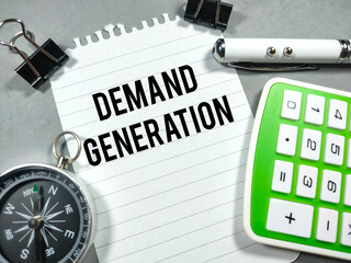 Business concept.Text DEMAND GENARATION writing on notepaper with paper clips,pen,compass and...