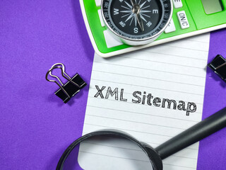 Business concept.Text XML Sitemap writing on notepaper with magnifying glass,compass,calculator and paper clips on purple background.