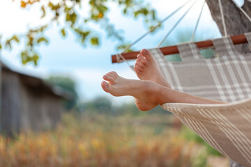 Boy legs on hammock at nature background. Relax in the hammock in the summer garden. Concept rest...