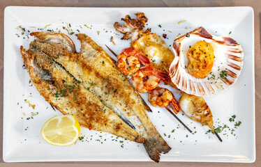Mixed grilled sea food. Sea bass, cuttlefish and prawns with lemon. Shrimp and oyster - 452873067