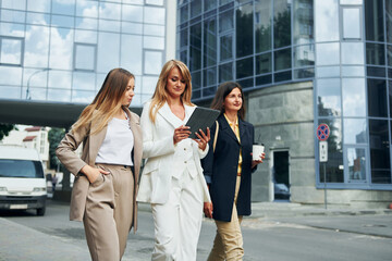Positive women in formal wear is outdoors in the city together