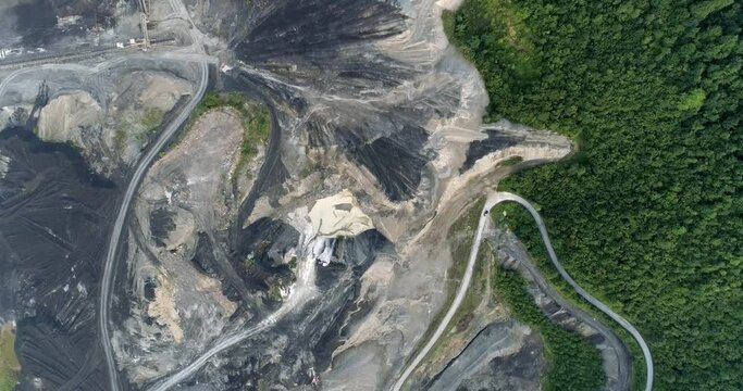 Aerial moving footage of a coal mine surrounded by woods
