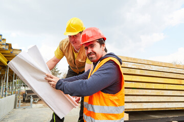 Architect and construction worker on construction site with floor plan