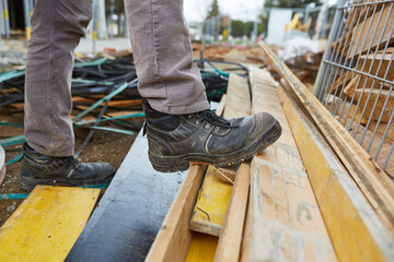 Safety shoes of workers on a construction site - obrazy, fototapety, plakaty