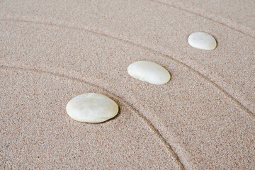 Obraz premium Zen garden stone Japanese on raked sand. rock or pebbles on beach design outdoor for meditate peace of mind and relax. Buddhism religion concept.