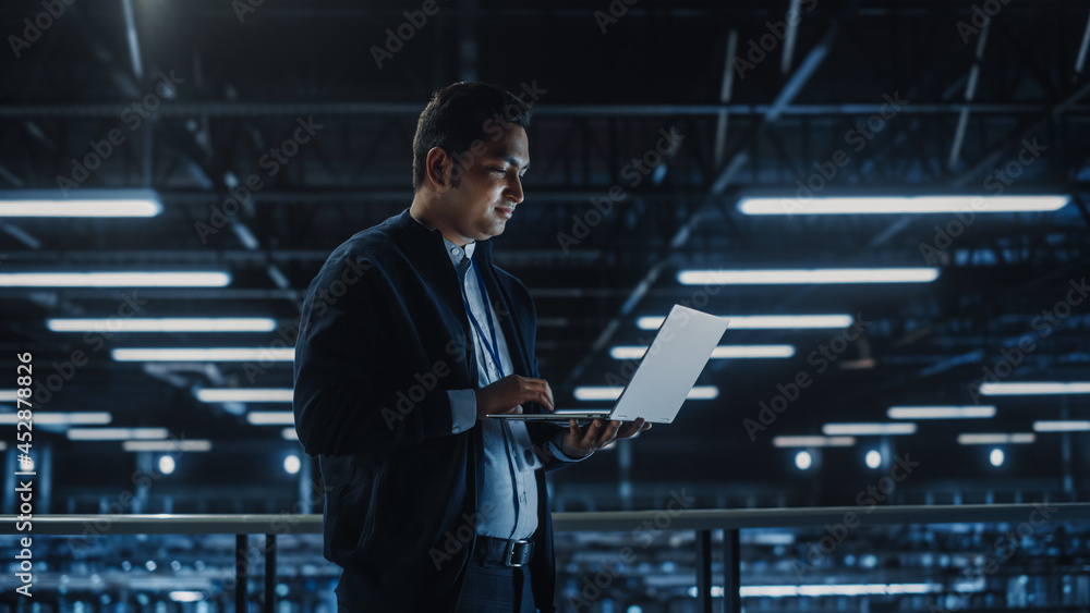 Poster Portrait of IT Specialist Uses Laptop in Data Center. Server Farm Cloud Computing Facility with Male Maintenance Administrator Working. Cyber Security and Network Protection.