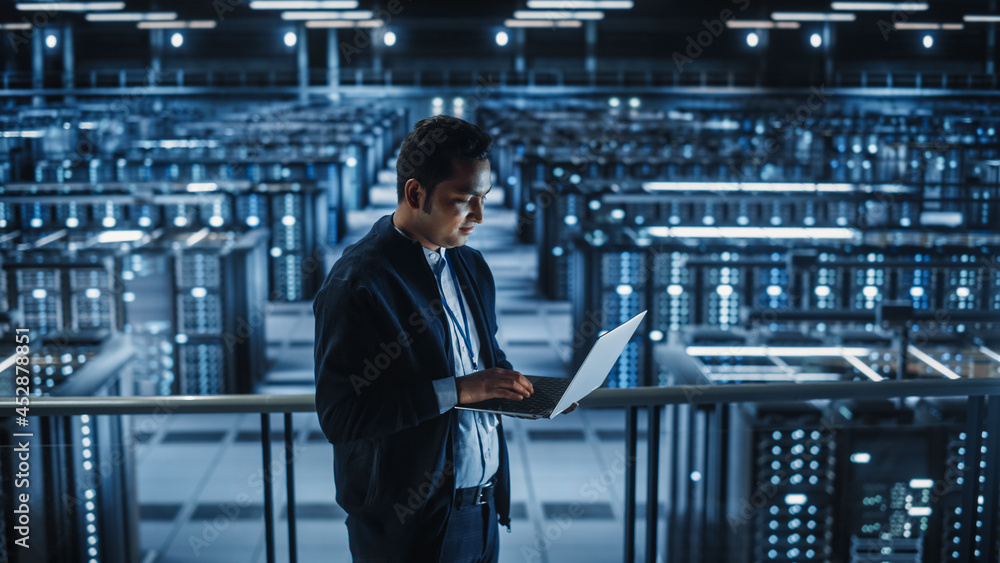 Poster portrait of it specialist uses laptop in data center. server farm cloud computing facility with male