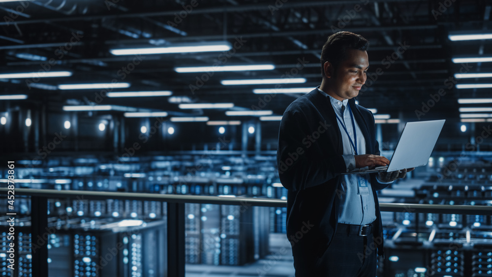 Leinwandbilder portrait of it specialist uses laptop in data center. server farm cloud computing facility with male