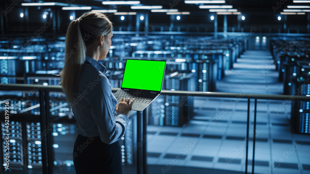 Poster female it specialist using chroma key laptop in data center. big server farm cloud computing facilit