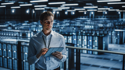 Portrait of Smiling IT Specialist Using Tablet Computer in Data Center. Big Server Farm Cloud Computing Facility with Male Maintenance Administrator Working. Cyber Security, e-Business.