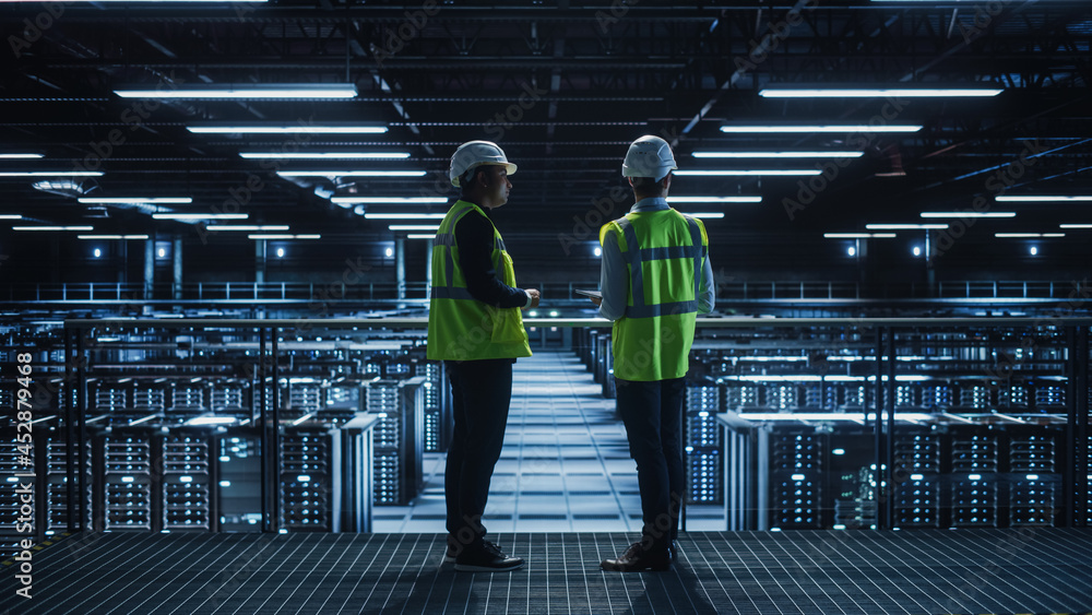 Leinwandbilder data center it specialist and system administrator talk, use tablet computer, wearing safety west. s
