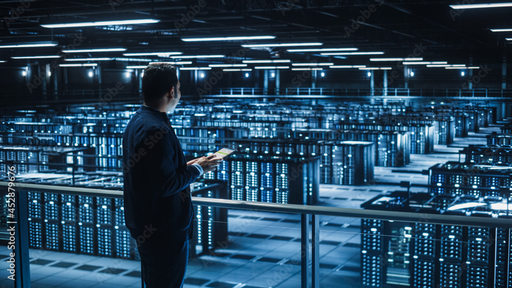 Aufkleber Handsome Smiling IT Specialist Using Tablet Computer in Data Center. Succesful Businessman and e-Business Entrepreneur Overlooking Server Farm Cloud Computing Facility.