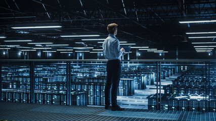 Handsome Smiling IT Specialist Using Tablet Computer in Data Center. Succesful Businessman and...