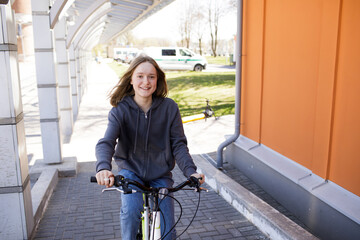 Teenager girl on a city bike. Portrait of a beautiful girl. Sunny summer weather. Casual hoody. Lifestyle people close up enjoying summer. Bicycle sustainable city mobility. Green transport to school