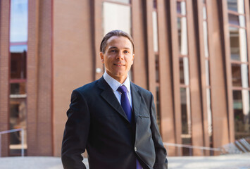 Confident businessman in front of modern office building. Financial investor is walking outdoor. Banking and business.