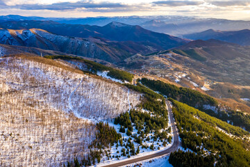 Kopaonik mountain range in Serbia. Aerial view on Kopainik National Park. Sunset under mountains, hills and meadows. Winding road along the mountains