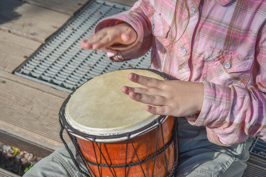 the girl child with a djembe drum outdoor on the porch of the house photo without processing
