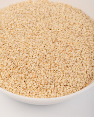 White sesame seeds in a white plate isolated on a white background. High quality photo
