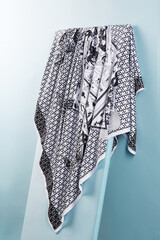 Subject photo of black and white scarf with fashion design. Stylish silk headkerchief is hanging on the white board.  