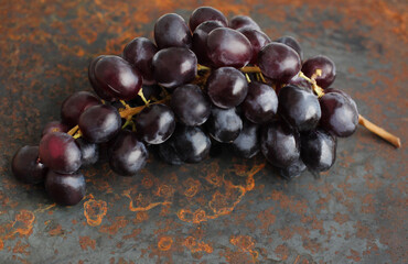 Black bunch of grapes on a metallic background with rust