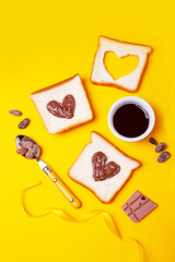 Toast sandwiches with chocolate paste on a yellow background. Romantic breakfast. Valentines day concept