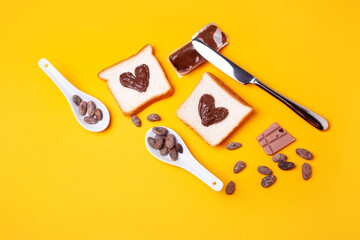 Heart shaped toast sandwiches with chocolate paste on a yellow background. Romantic breakfast. Valentines day concept