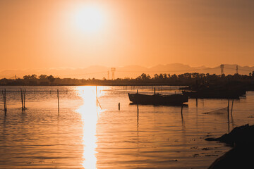 Fototapeta premium Silhouette view of little boats and sunlight at Giliacquas park and view of his pond at sunset