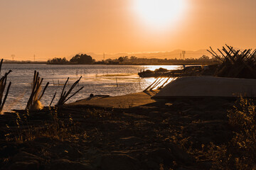 Long distance view of a fisherman fishing on the pond at the park of Giliacquas at sunset, with empty boats, fish nets, rocks and calm water