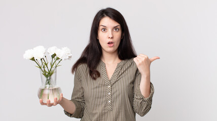 pretty woman looking astonished in disbelief and holding a decorative flowers. assistant agent with...