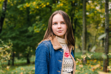 Beautiful girl with long hair in a blue denim coat in an autumn park