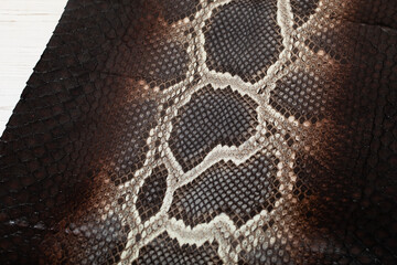 Brown dyed folded natural genuine python leather on the wooden table
