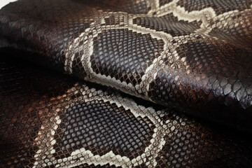 Brown dyed folded natural genuine python leather on the wooden table