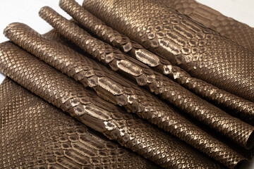 Brown dyed folded natural genuine python leather on the wooden table